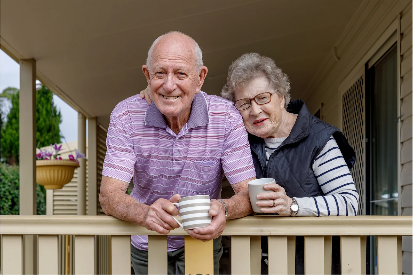 Happy senior couple enjoying coffee together on their porch at an active adult community