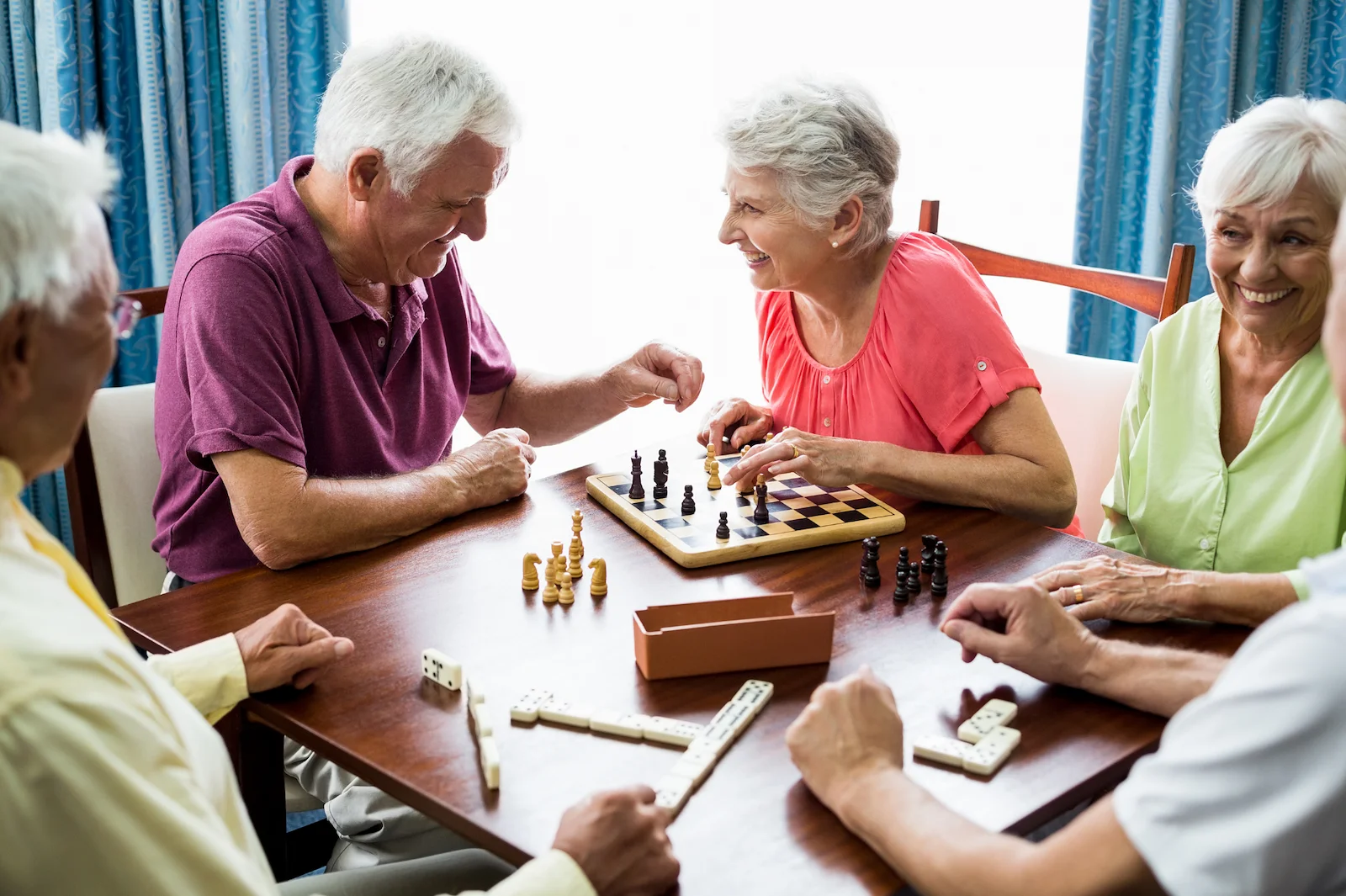 Group of seniors playing chess and board games together at a community center
