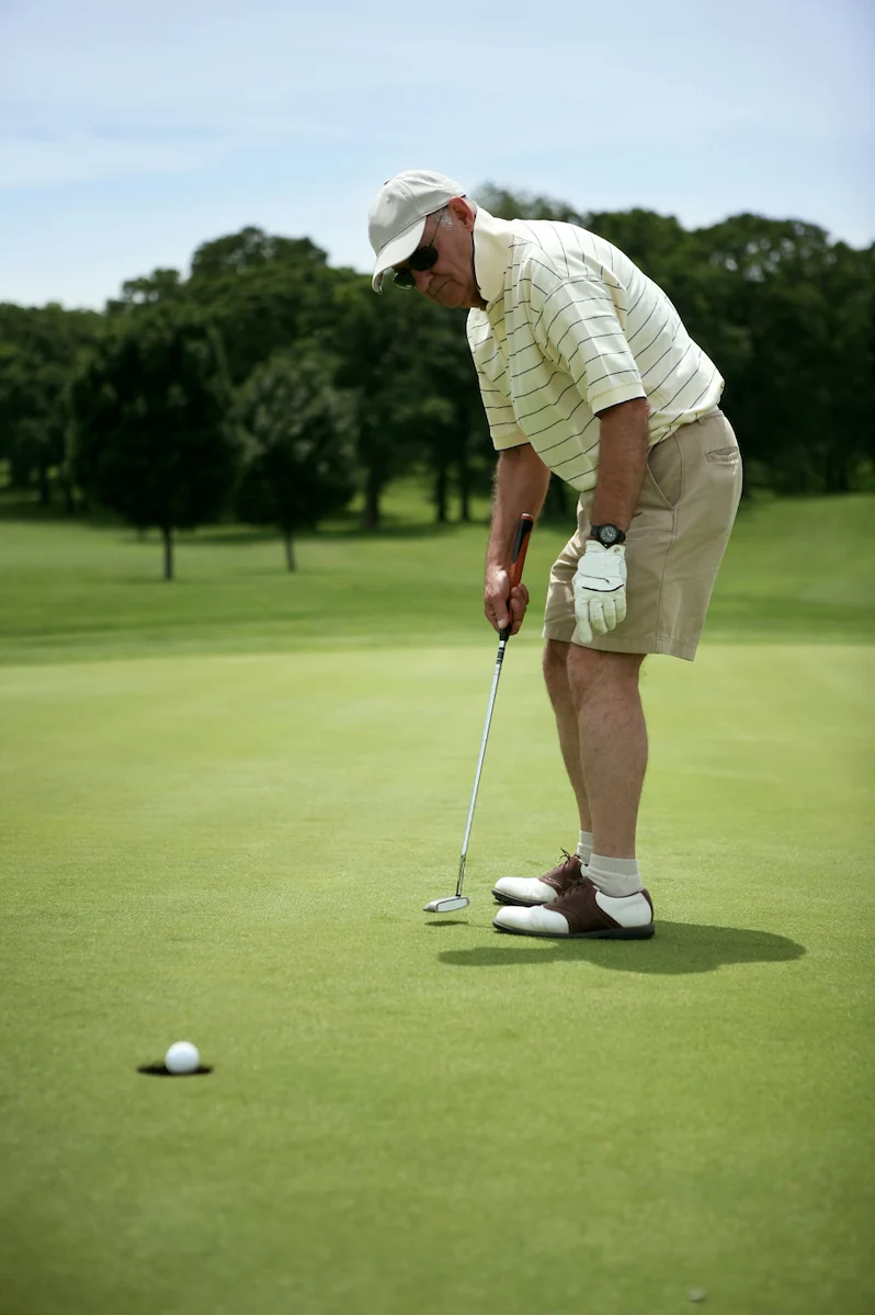 Senior man putting on the green at a golf course on a sunny day
