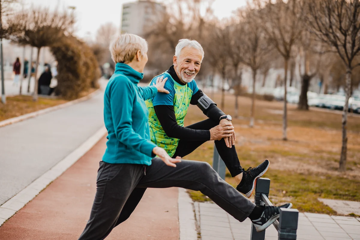Senior couple stretching together during an outdoor workout in the park