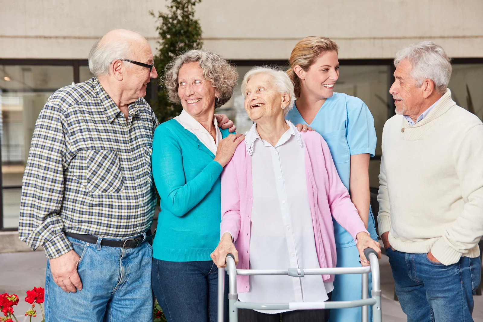 Caregiver and seniors socializing together outside adult day care near you