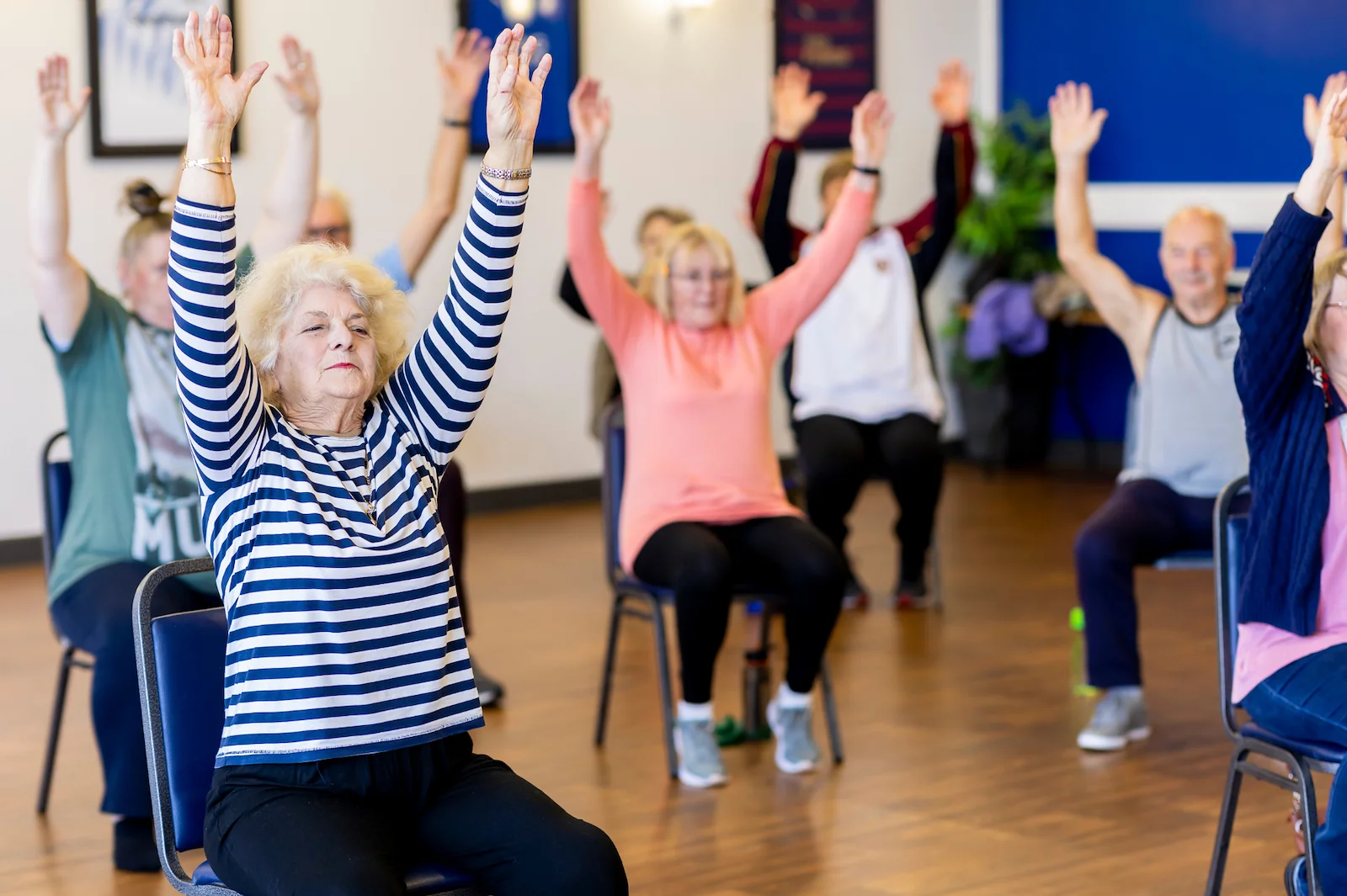 Group of seniors doing chair-based stretching exercises in a fitness class