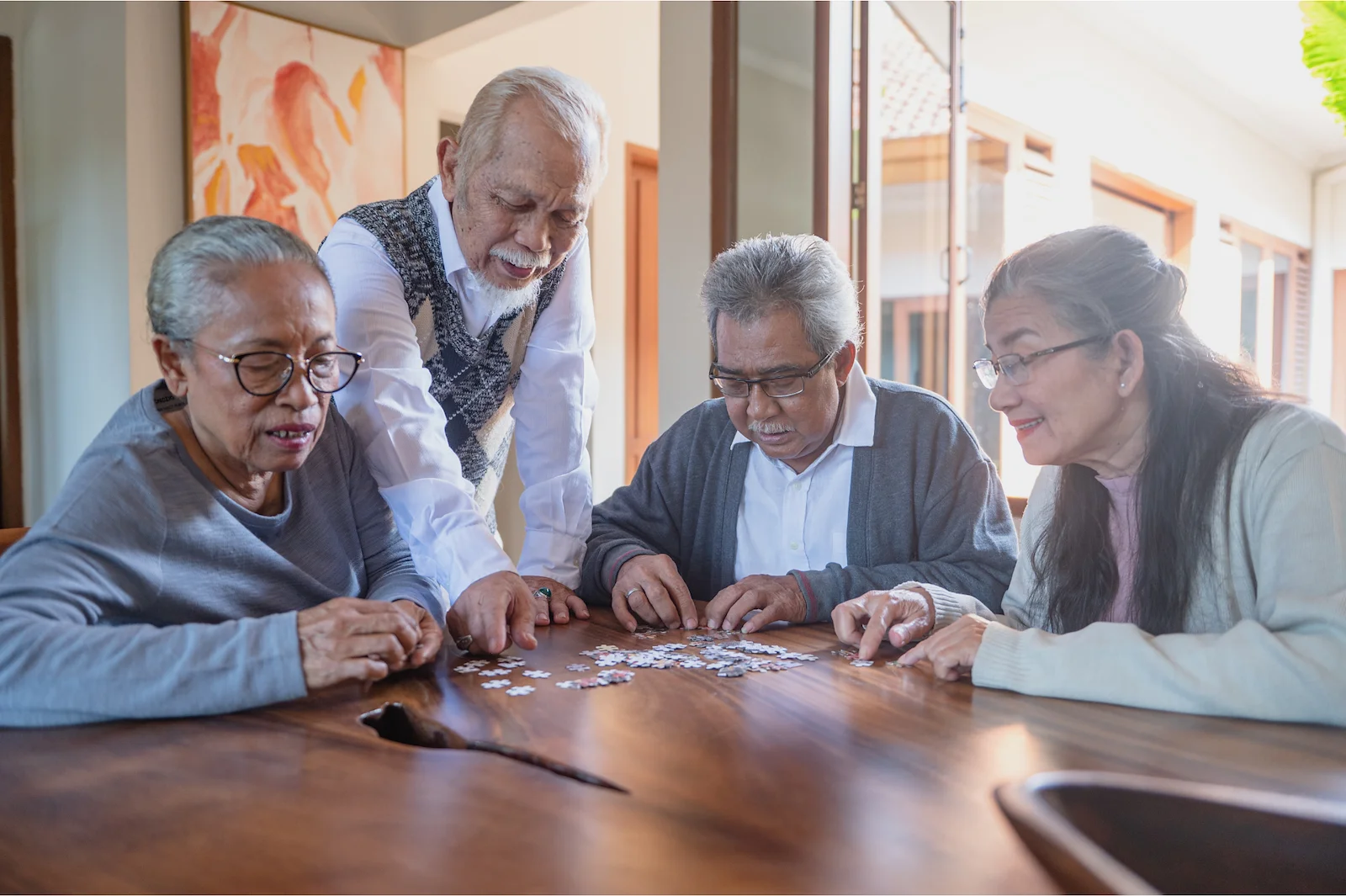 Group of seniors working together on a jigsaw puzzle at a dining table
