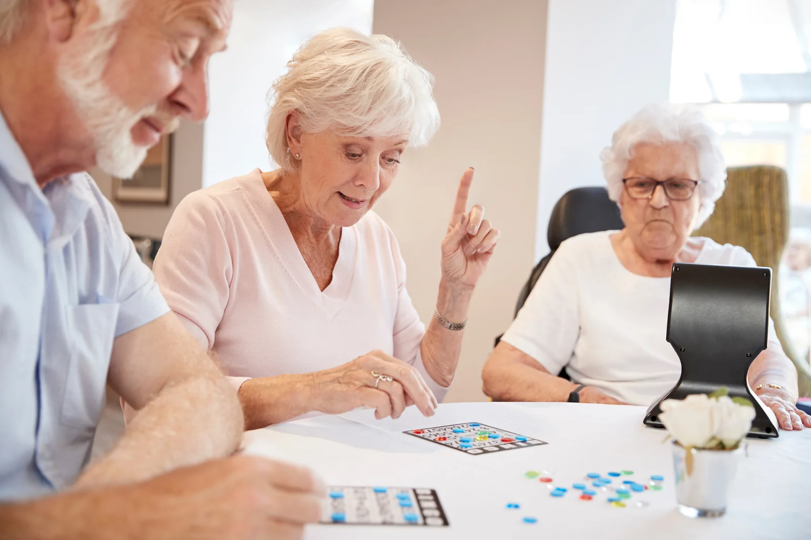 Seniors playing a bingo game together at a bright community room table