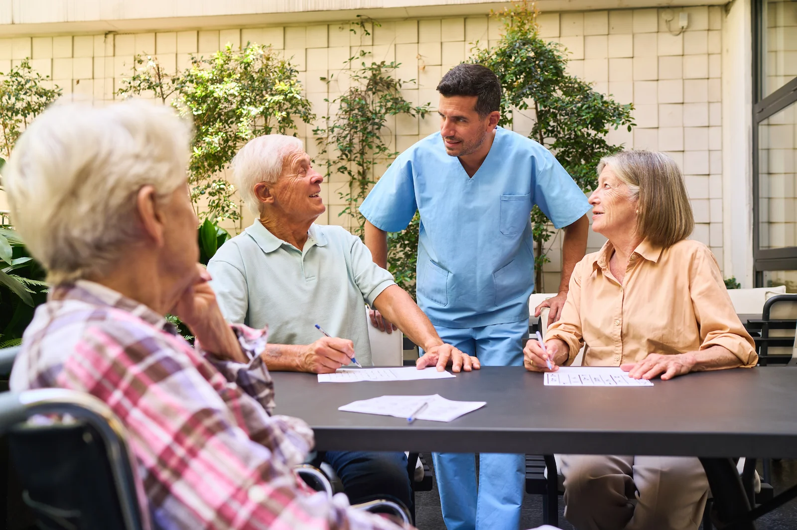 Healthcare professional leading a group activity with seniors at an outdoor patio table