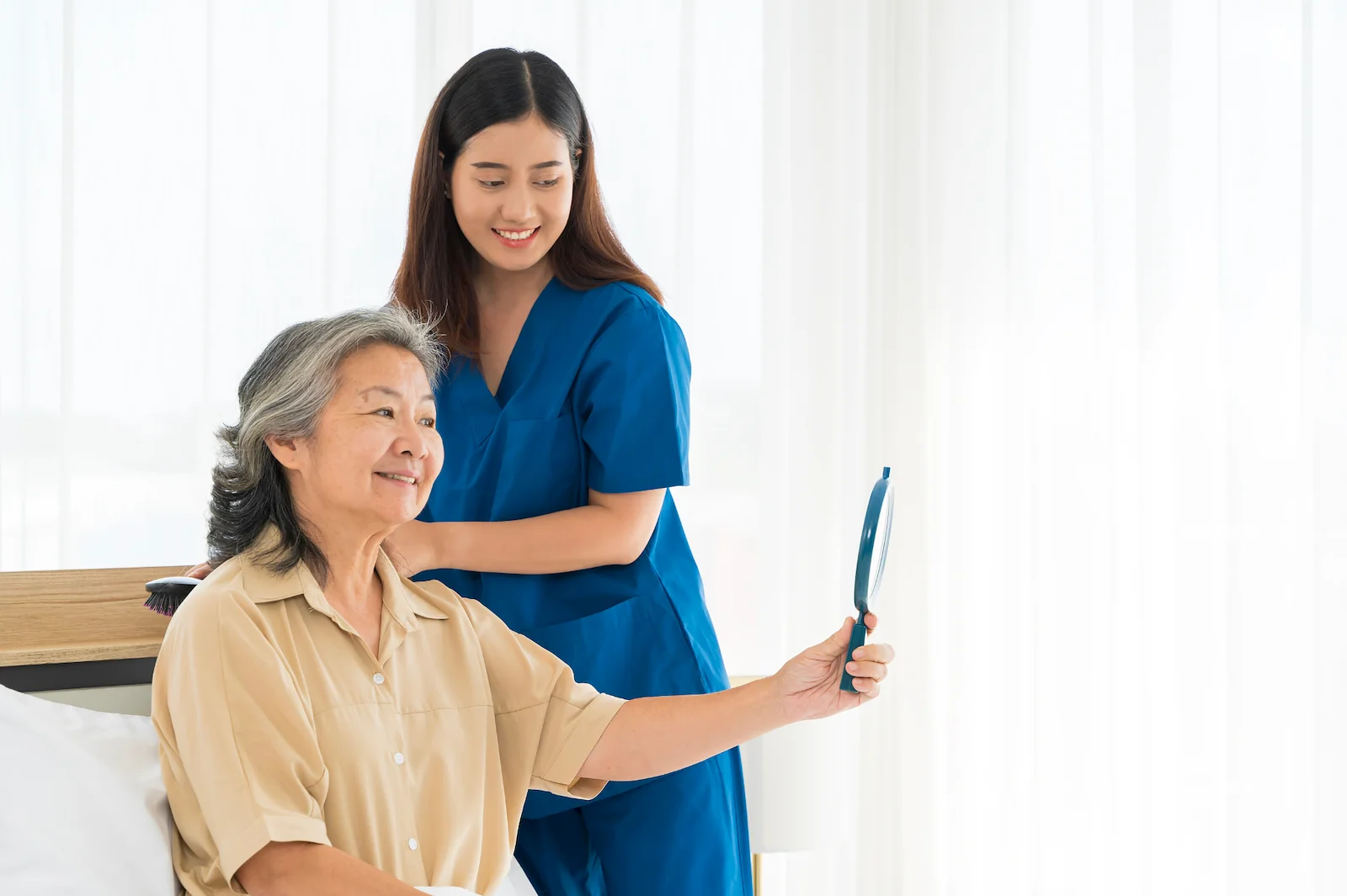 Caregiver sharing a joyful moment with senior woman over coffee and photos