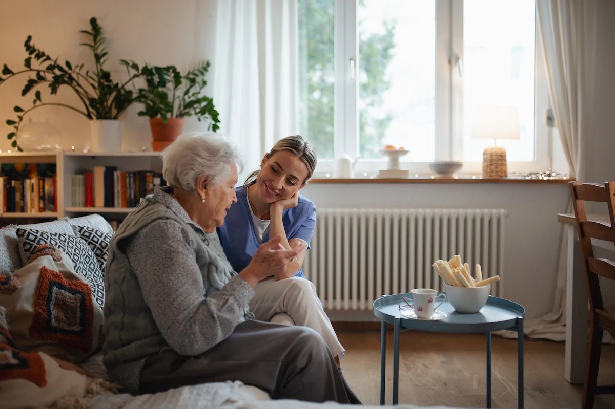 Caregiver having a warm conversation with senior woman in a cozy apartment