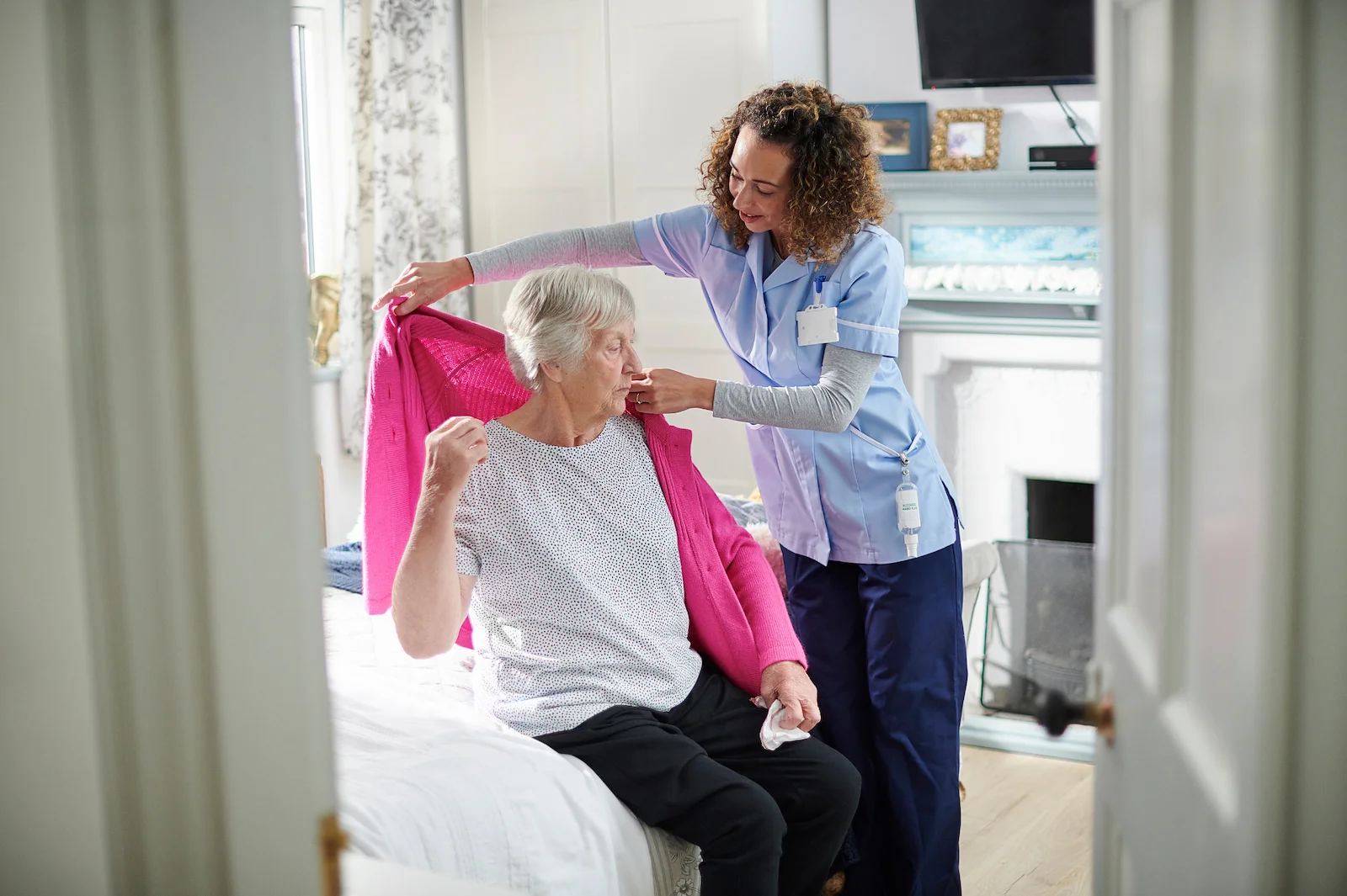 Caregiver pouring coffee for seniors enjoying breakfast together at a dining table