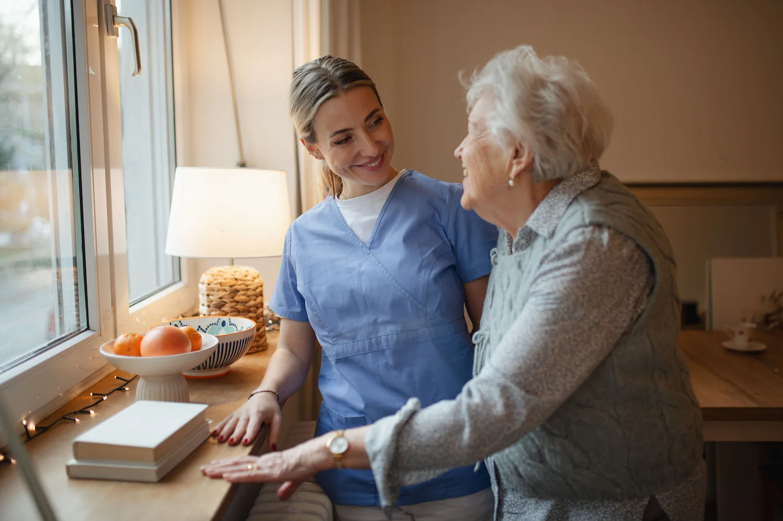 Caregiver providing compassionate home care near you to senior woman in a bright kitchen