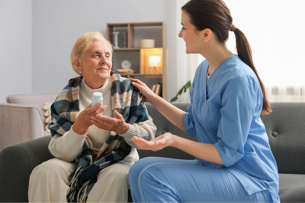 Nurse providing medication management to senior woman on a sofa