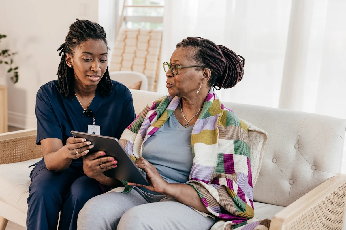 Nurse reviewing care plan with senior woman on tablet at home