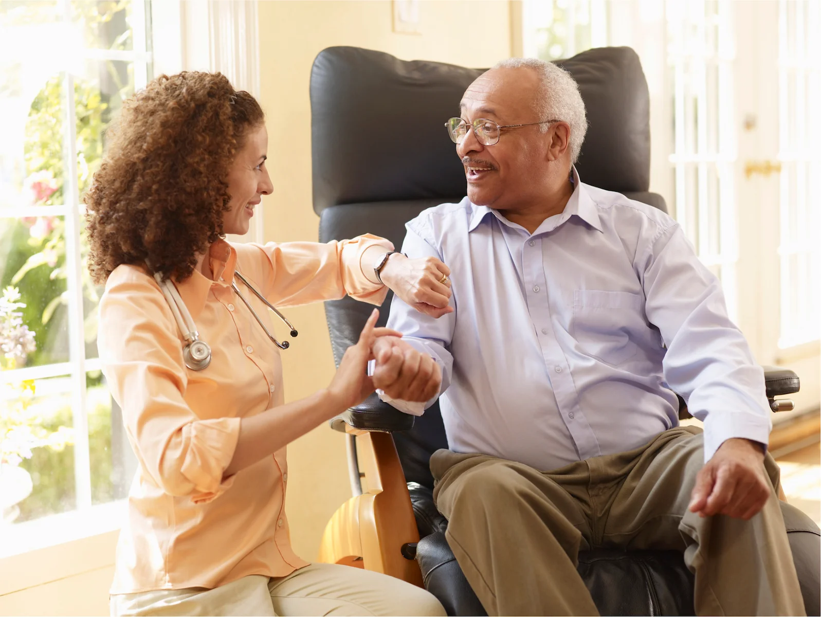 Nurse helping senior man with physical therapy exercises in a wheelchair at home