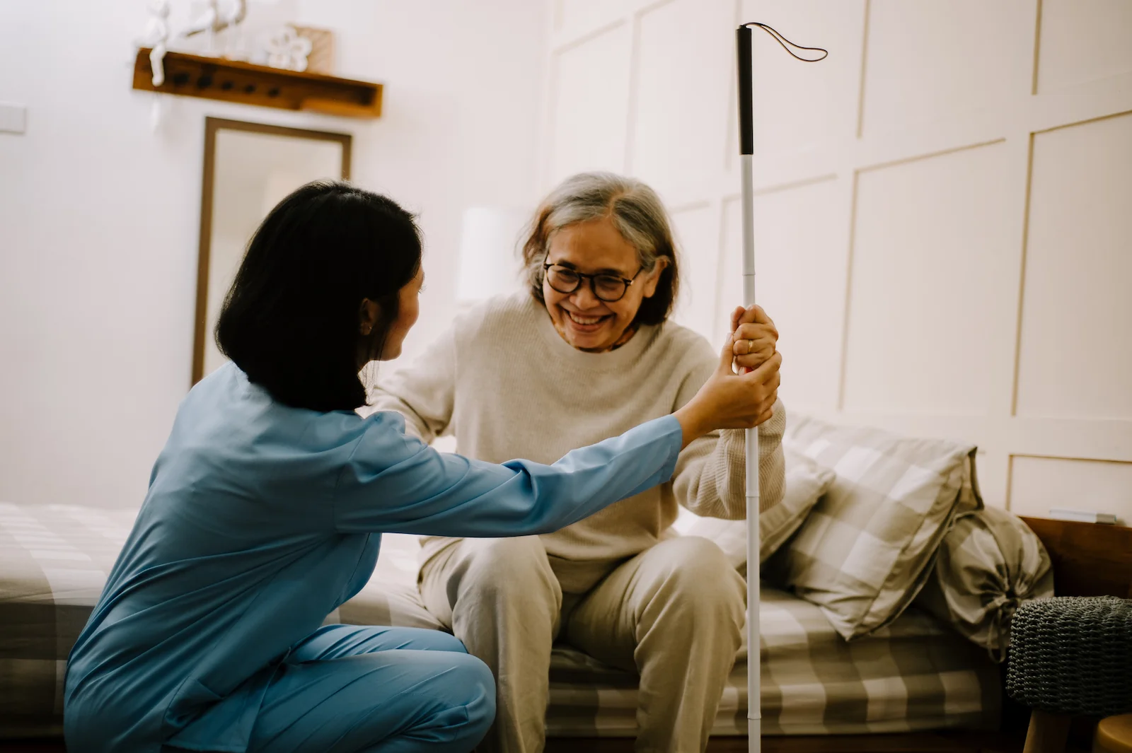 Caregiver assisting senior woman with mobility using a cane at home