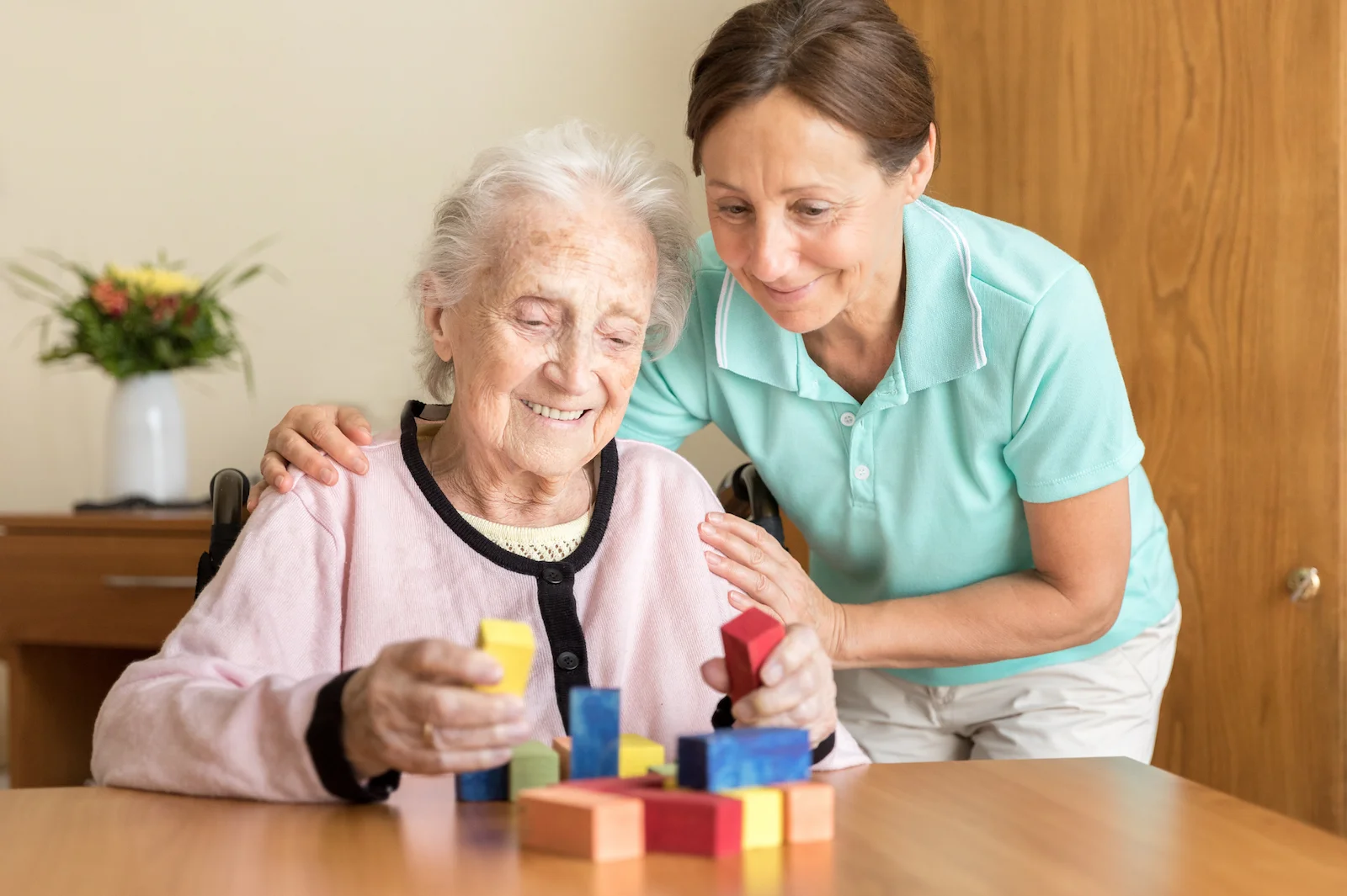 Therapist guiding senior through cognitive skills activity with colorful blocks