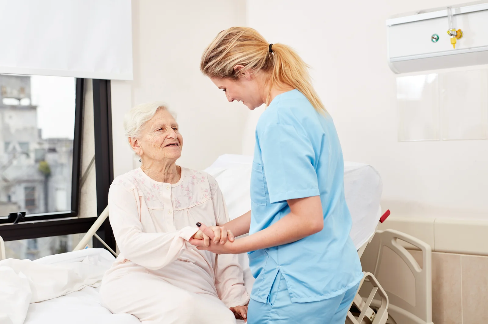 Nurse helping elderly patient with bedside mobility assistance