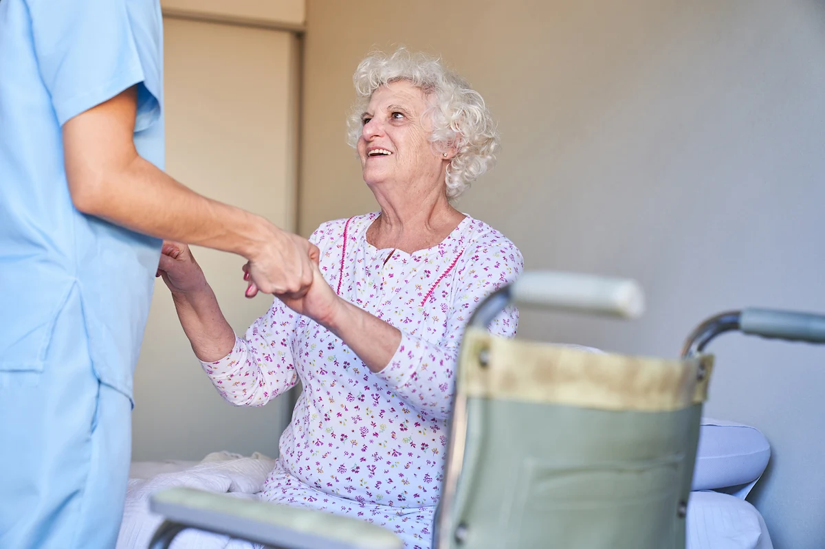 Nurse assisting joyful senior with mobility and daily activities