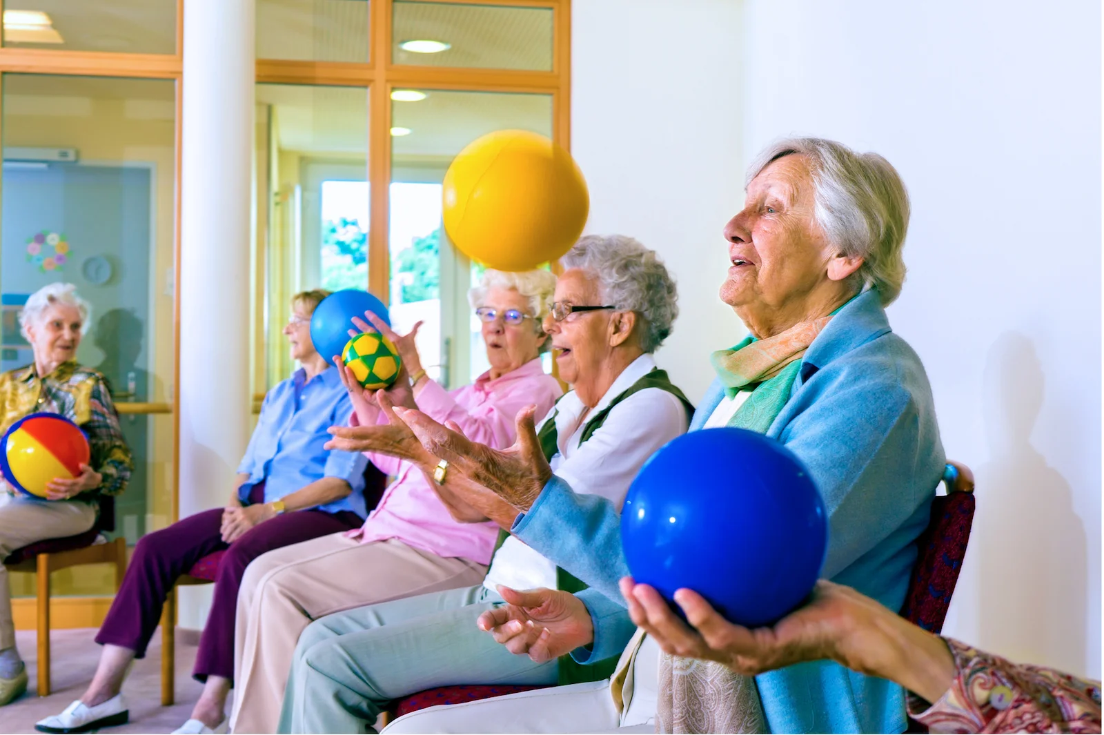 Seniors participating in seated exercise class with colorful therapy balls