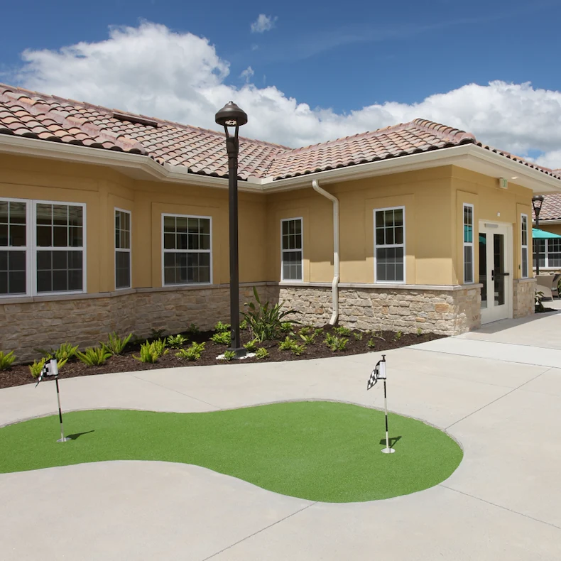 Liana of Venice senior living community offering assisted living and memory care in Venice, FL, exterior featuring a small putting green