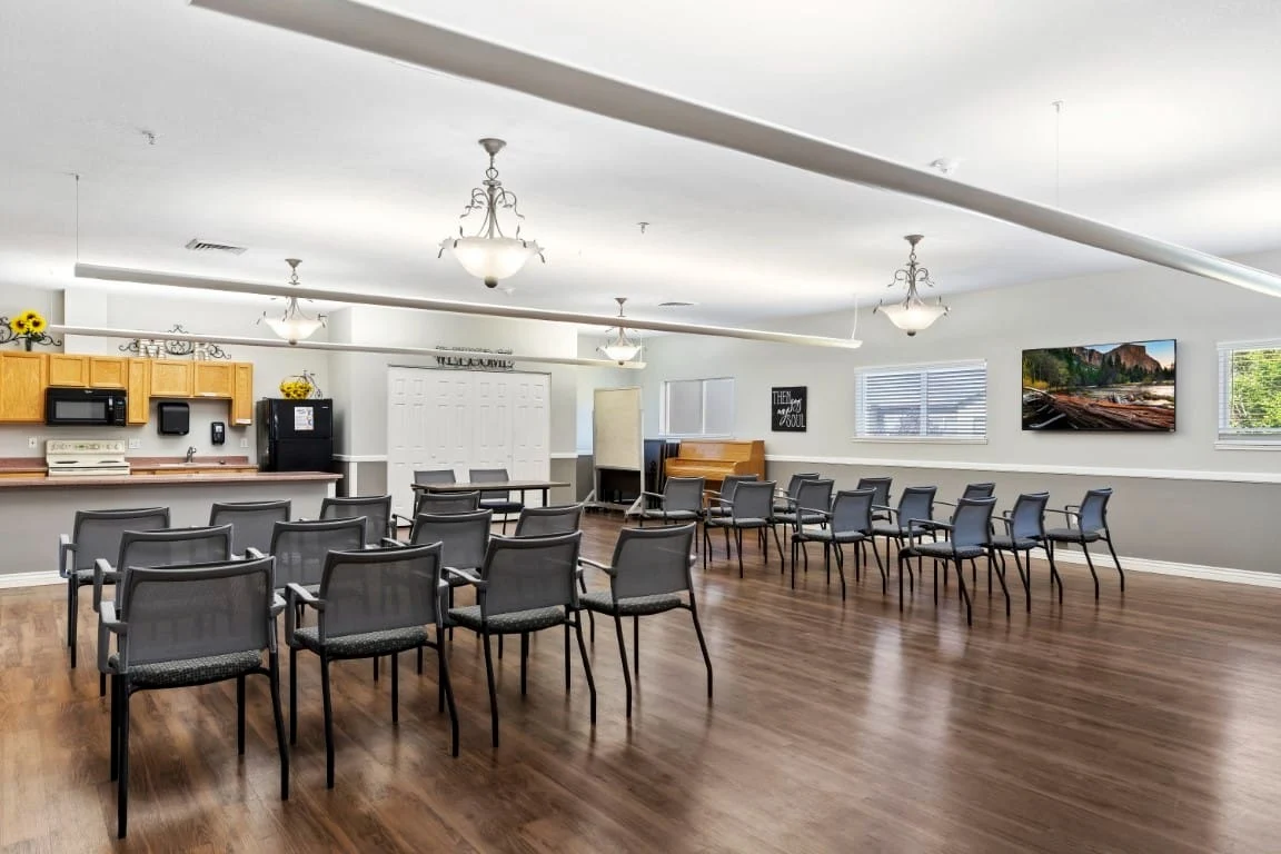 Avamere at Mountain Ridge senior living community offering assisted living, memory care, and respite care in South Ogden, UT, open activities room with chairs arranged for a group event and a kitchenette in the background