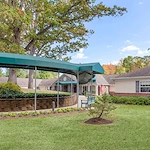 Covered walking path with shade and a bench outside Charter Senior Living of Jackson in Jackson, TN, offering a comfortable outdoor space for assisted living and memory care residents to relax and enjoy fresh air.