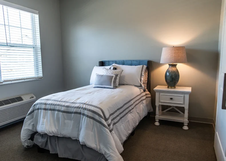 Comfortable bedroom with large window and cozy decor at Charter Senior Living of Hopkinsville in Hopkinsville, KY, designed for assisted living and memory care residents.