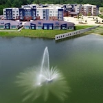 Watermere at Woodland Lakes senior living community offering active adult living and independent living in Conroe, TX, exterior with water fountain in nearby pond
