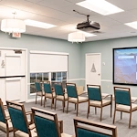 Well-lit movie lounge with large screen and seating at Charter Senior Living of Hazel Crest in Hazel Crest, IL, serving assisted living & memory care.
