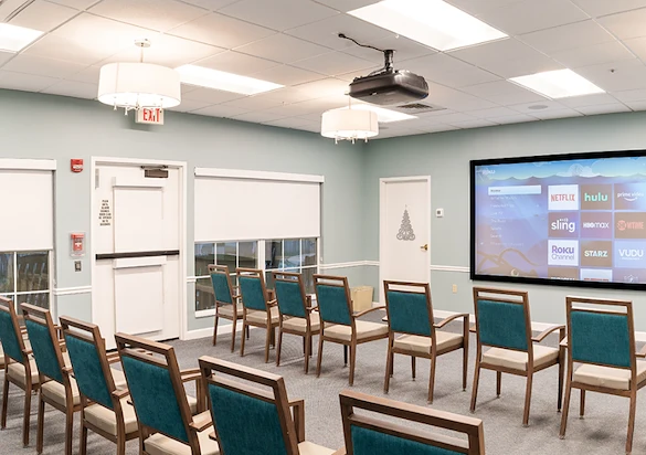 Well-lit movie lounge with large screen and seating at Charter Senior Living of Hazel Crest in Hazel Crest, IL, serving assisted living & memory care.