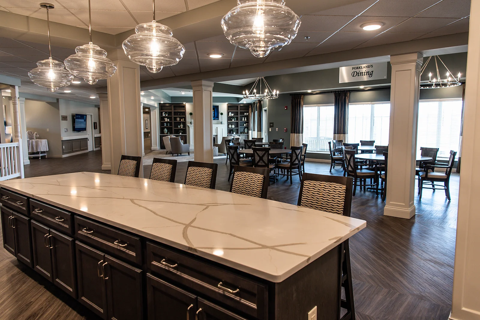 Inviting dining and lounge area at Charter Senior Living of Hopkinsville in Hopkinsville, KY, with countertop seating, tables and chairs for gathering, and a cozy sitting area—ideal for assisted living and memory care residents.