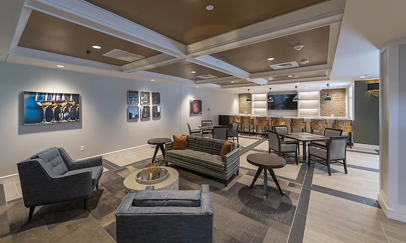 Alto Evergreen Walk, senior living community offering assisted living, memory care, and respite care in South Windsor, CT, lounge area with comfortable seating, tables and chairs, and bar-top seating 