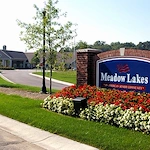 Meadow Lakes Senior Assisted Living in Mooresville, IN front exterior entrance driveway with welcome sign that says "Meadow Lakes 'An American Senior Community'"