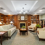 Brightmore of South Charlotte senior living community offering independent living, assisted living, and memory care in Charlotte, NC, library featuring comfortable seating, well-stocked bookshelves, and a cozy fireplace
