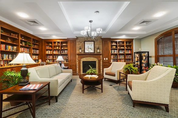 Brightmore of South Charlotte senior living community offering independent living, assisted living, and memory care in Charlotte, NC, library featuring comfortable seating, well-stocked bookshelves, and a cozy fireplace