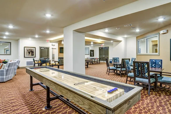Watermere at Round Rock senior living community offering active adult living and independent living in Round Rock, TX, activities room featuring a shuffleboard table and other tables and chairs for games