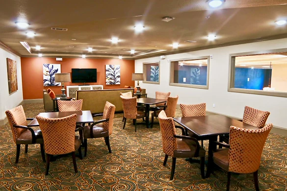 Active adult living and independent living at Watercrest at Shadow Creek Ranch in Pearland, TX, common area with tables for activities and comfortable seating by a TV