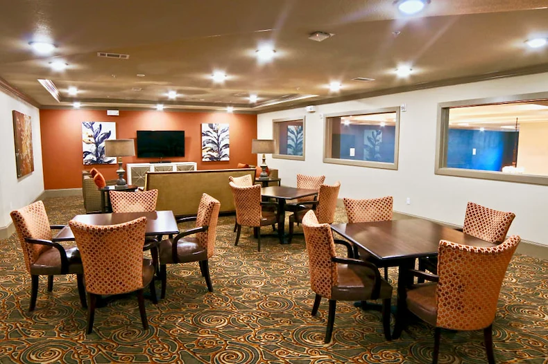 Active adult living and independent living at Watercrest at Shadow Creek Ranch in Pearland, TX, common area with tables for activities and comfortable seating by a TV