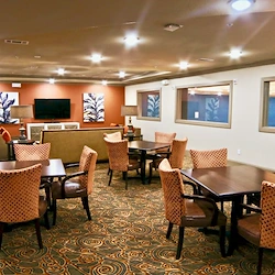 Active adult living and independent living at Watercrest at Shadow Creek Ranch in Pearland, TX, common area with tables for activities and comfortable seating by a TV