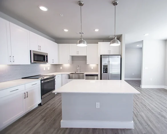 Watermere at Flower Mound senior living community offering active adult living and independent living in Flower Mound, TX, apartment kitchen with white cabinets, white countertops, and stainless steel appliances
