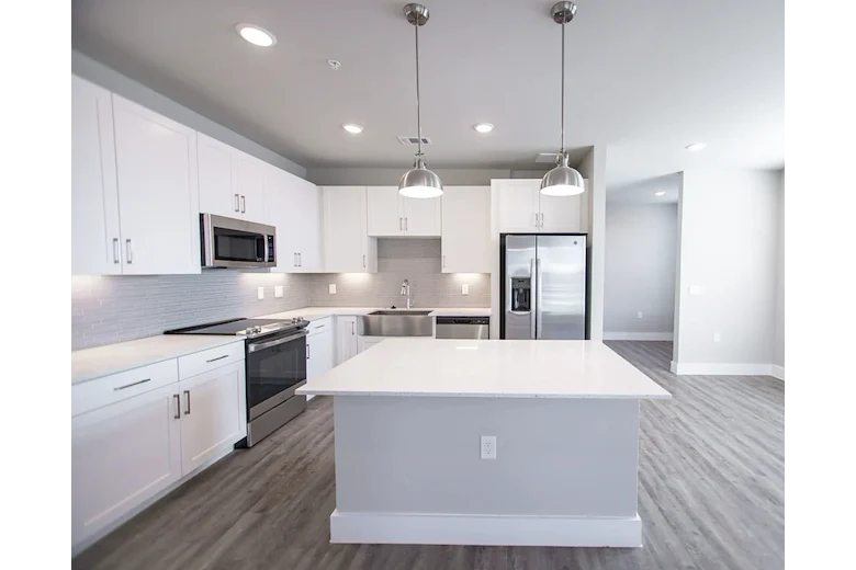 Watermere at Flower Mound senior living community offering active adult living and independent living in Flower Mound, TX, apartment kitchen with white cabinets, white countertops, and stainless steel appliances