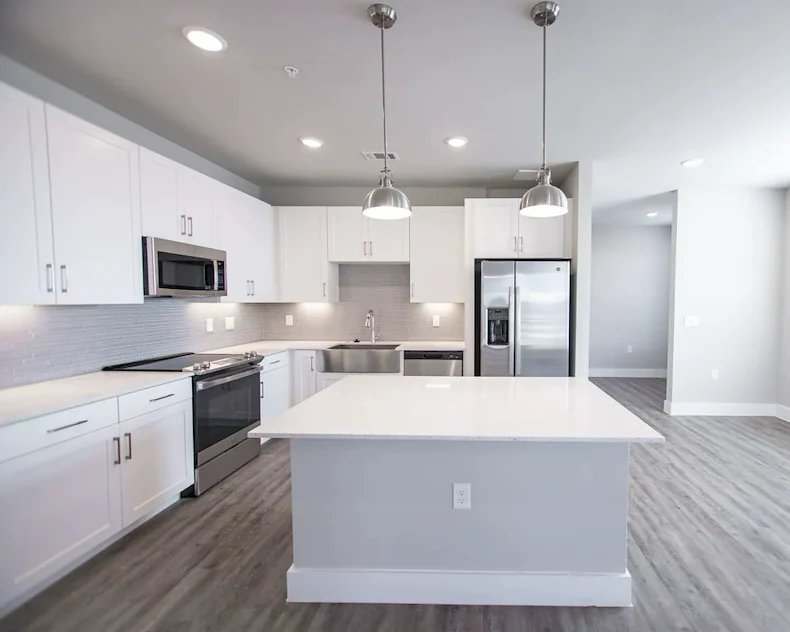Watermere at Flower Mound senior living community offering active adult living and independent living in Flower Mound, TX, apartment kitchen with white cabinets, white countertops, and stainless steel appliances