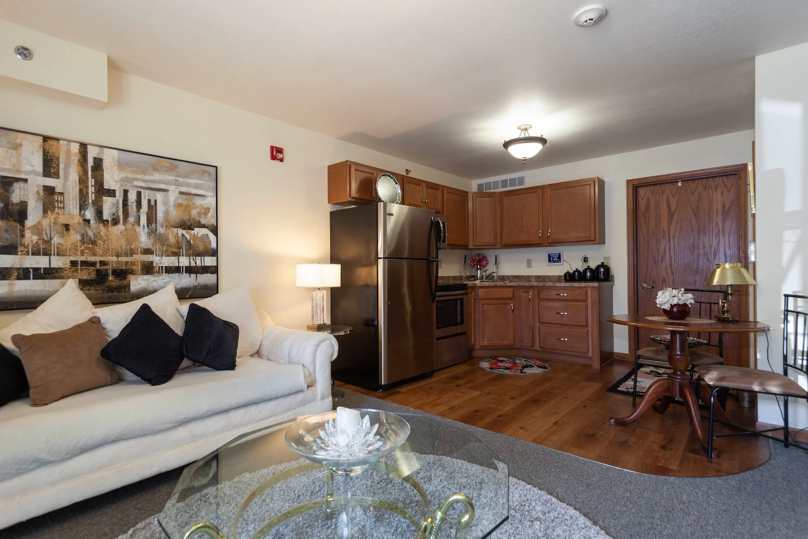 Spacious assisted living apartment at Charter Senior Living of Hasmer Lake in Jackson, WI, featuring a welcoming living area and full kitchen with full-size refrigerator and oven.