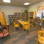 Lexington Assisted Living senior living community offering independent living, assisted living, and memory care in Ventura, CA, library with bookshelves, tables for puzzles, and a computer workstation