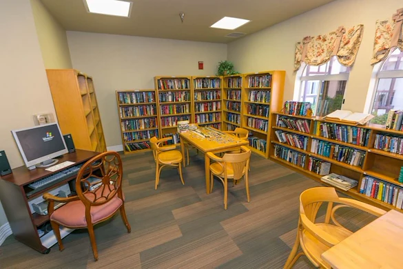 Lexington Assisted Living senior living community offering independent living, assisted living, and memory care in Ventura, CA, library with bookshelves, tables for puzzles, and a computer workstation
