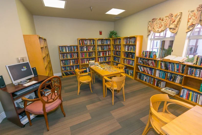 Lexington Assisted Living senior living community offering independent living, assisted living, and memory care in Ventura, CA, library with bookshelves, tables for puzzles, and a computer workstation