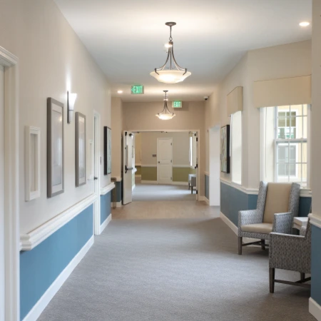 Liana of Sarasota senior living community offering assisted living and memory care in Sarasota, FL, hallway to resident apartments with warm lighting and a small sitting area