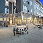 Alto Wheaton, senior living community offering assisted living, memory care, and respite care in Wheaton, IL, outdoor seating area with tables and chairs on a large paved patio