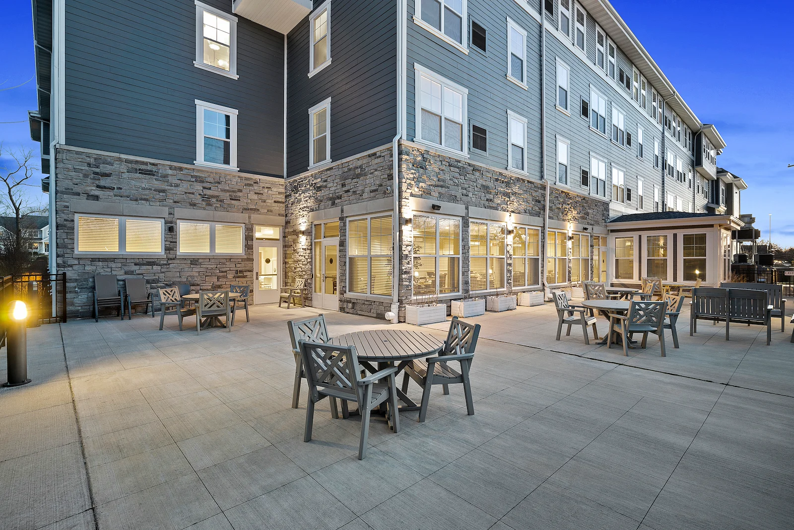 Alto Wheaton, senior living community offering assisted living, memory care, and respite care in Wheaton, IL, outdoor seating area with tables and chairs on a large paved patio