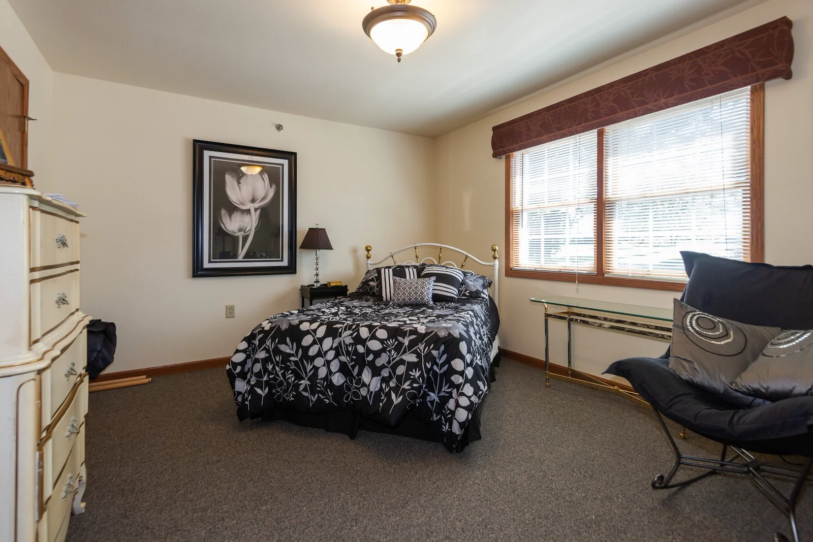 Cozy assisted living bedroom at Charter Senior Living of Hasmer Lake in Jackson, WI, with natural lighting and wall art for a home-like feel.
