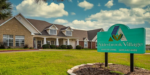 Alderbrook Village assisted living community in Arkansas City, KS, exterior view with community sign in yard and landscaped surroundings