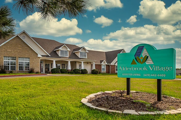 Alderbrook Village assisted living community in Arkansas City, KS, exterior view with community sign in yard and landscaped surroundings